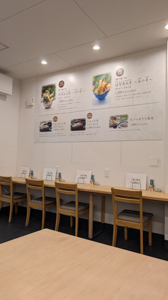 七瀬川食堂の店内カウンター席と壁の大型メニューパネル