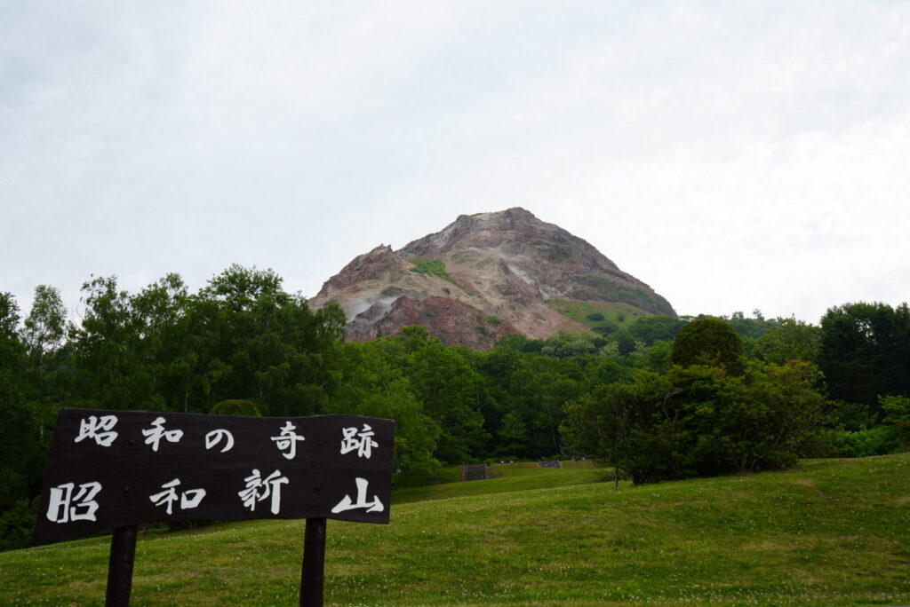昭和の奇跡・昭和新山の看板と赤茶色の山肌