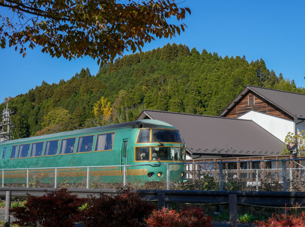 豊後森機関庫横を通過する緑色の特急ゆふいんの森号