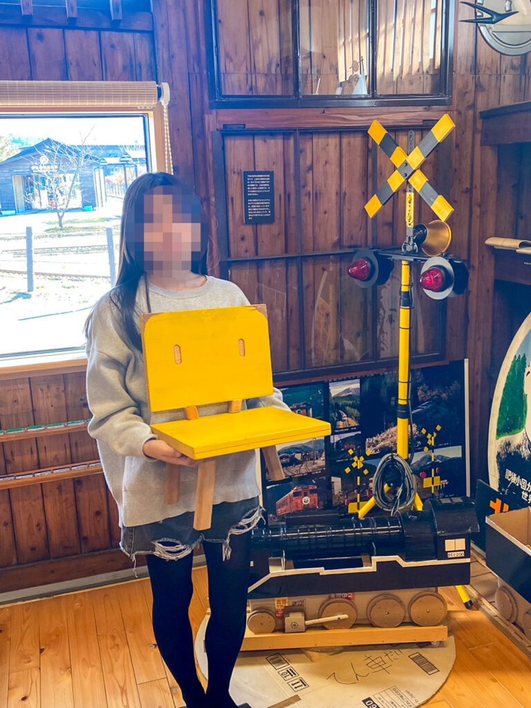 すずめの椅子を手に持つ人物と踏切展示のある館内
