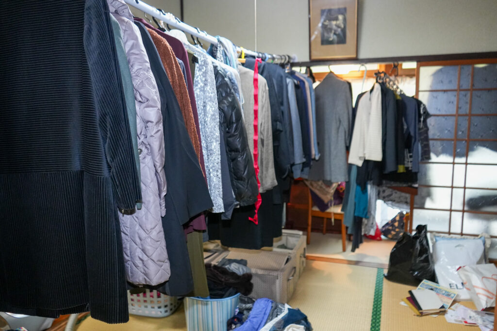 部屋のハンガーラックにびっしり並んだ整理前の衣類
