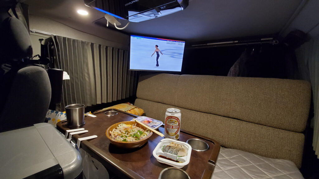 ハイエース車内でテレビを見ながら夕食をとる車中泊の夜